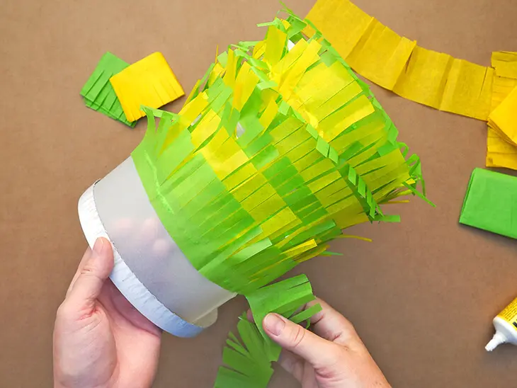 Jemand klebt fransige Seidenpapierstreifen auf einen Laternenrohling von HEYDA und Knorr prandell. Foto: Johanna Rundel