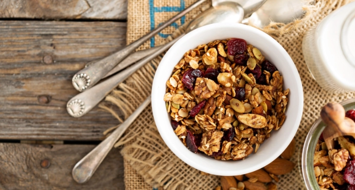 Schüssel mit gesundem Müsli und Milch auf Holztisch